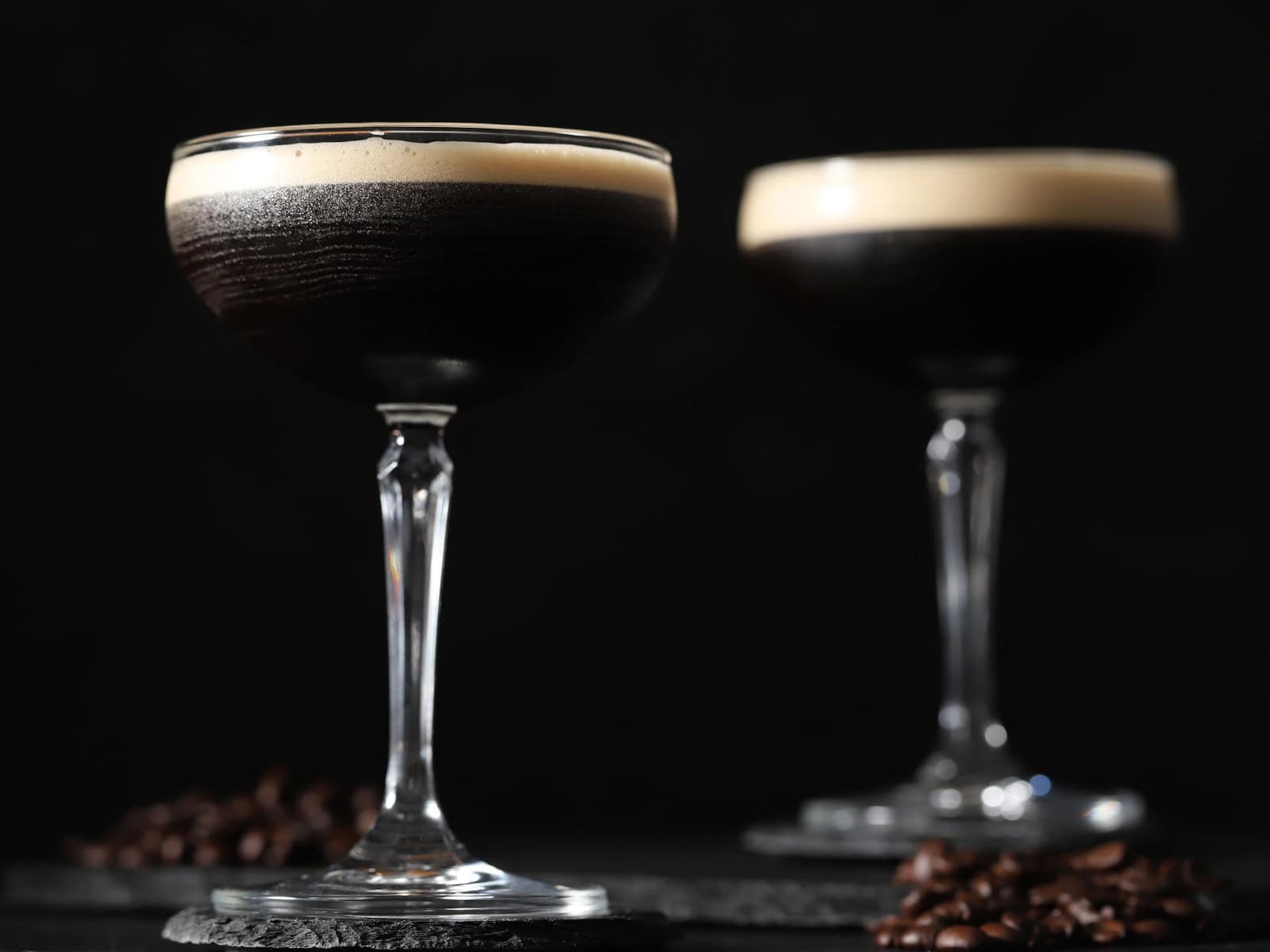 Two glasses filled with espresso martini with foam on top.