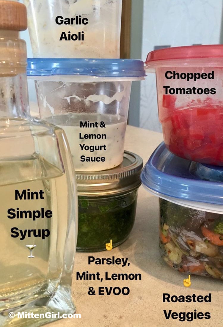 Meal prep ideas and options with containers of mint simple syrup, mint and lemon yogurt sauce, chopped tomatoes, roasted veggies, and parsley, mint, lemon and olive oil. 