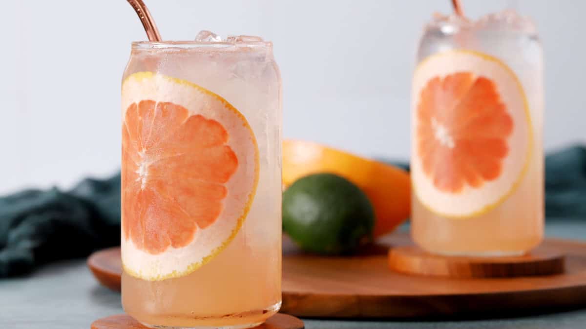 Two glasses of Palomas garnished with large slices of grapefruit.