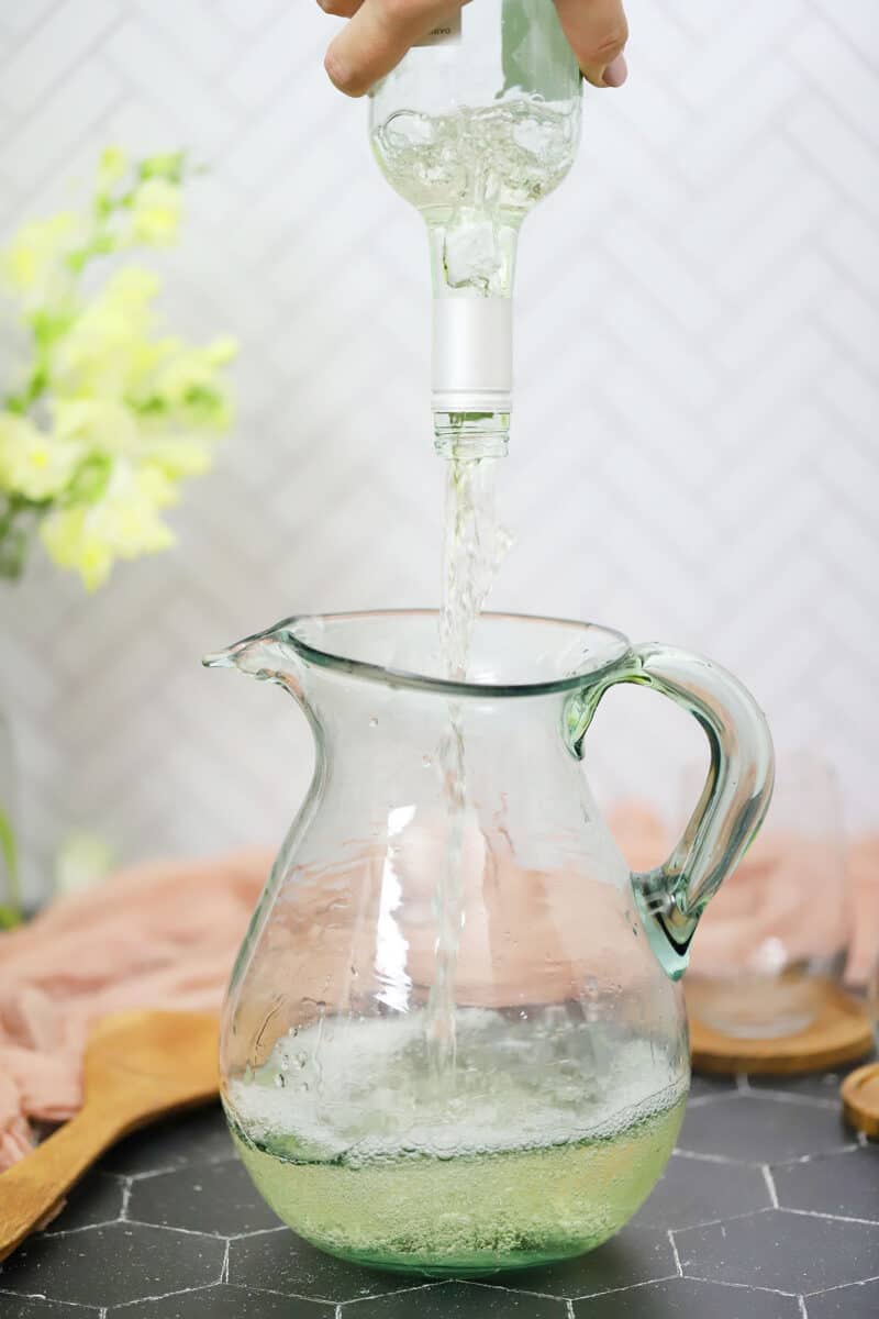 White wine being poured into a pitcher. 