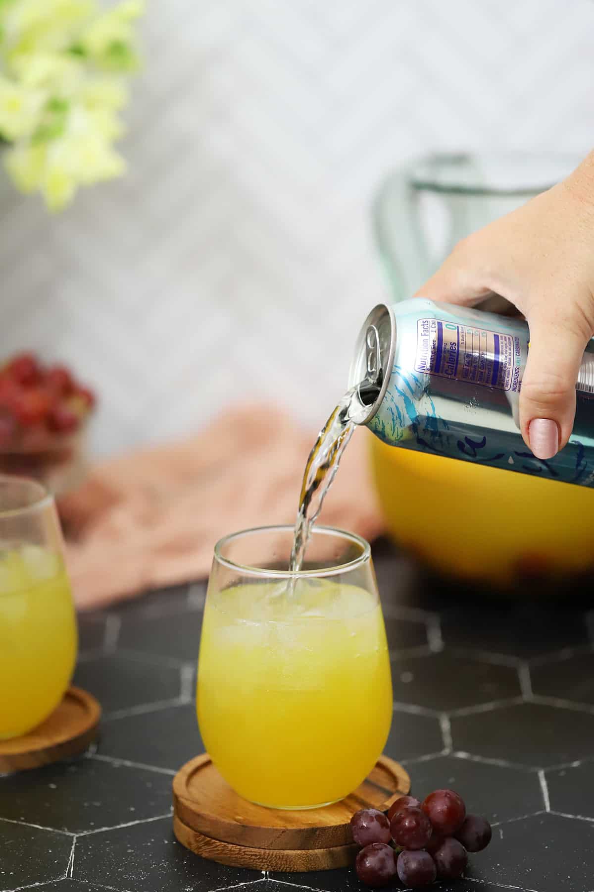 Pouring soda water on top of a glass of sangria.