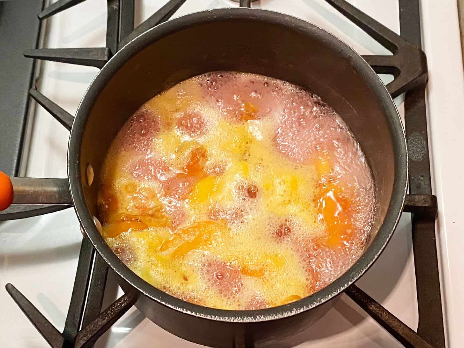 Peaches, sugar and water cooking in a pot