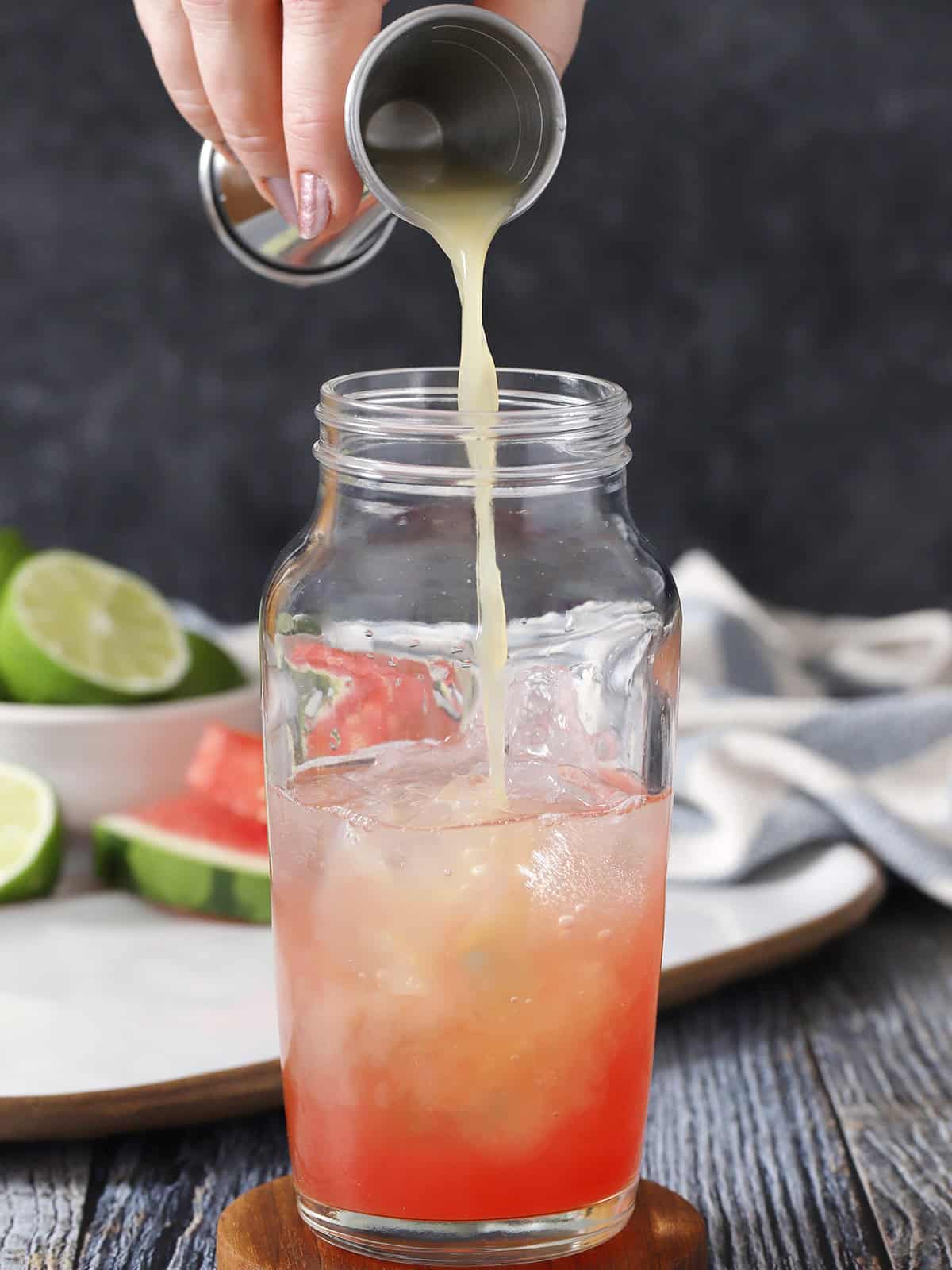 Lime juice being poured into a cocktail shaker. 