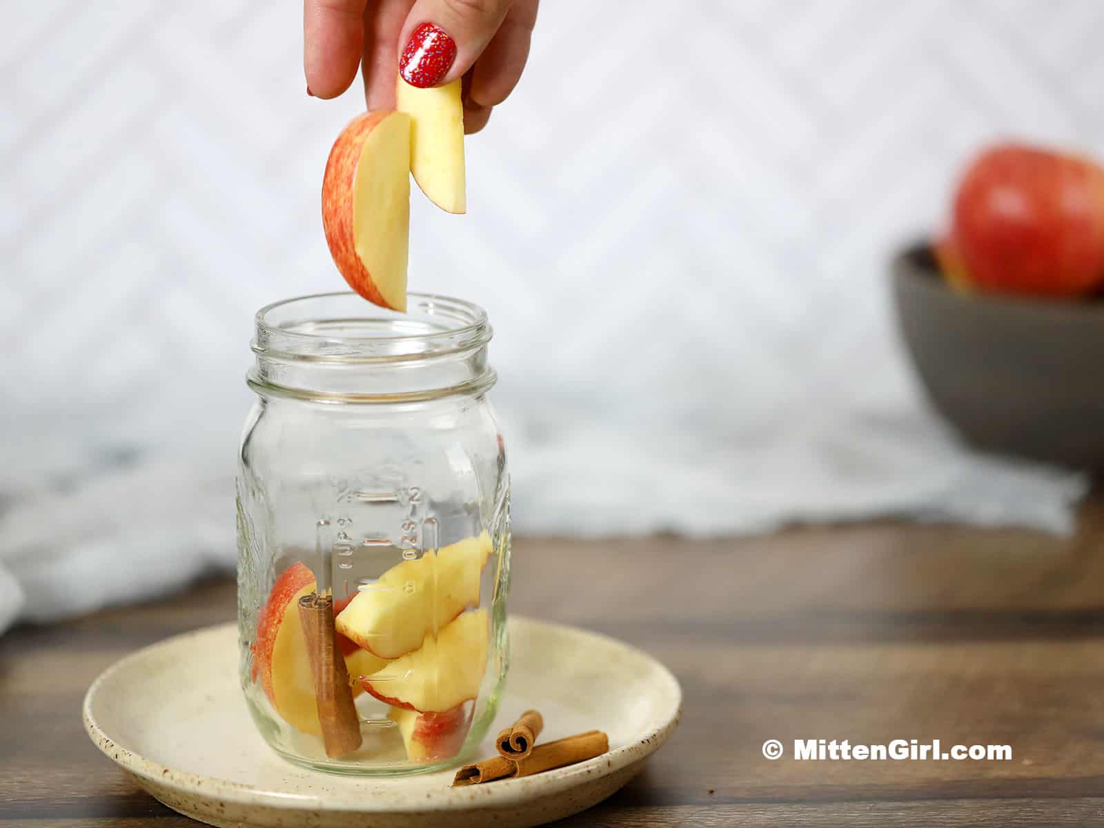 Apple slices being dropped in a mason jar.
