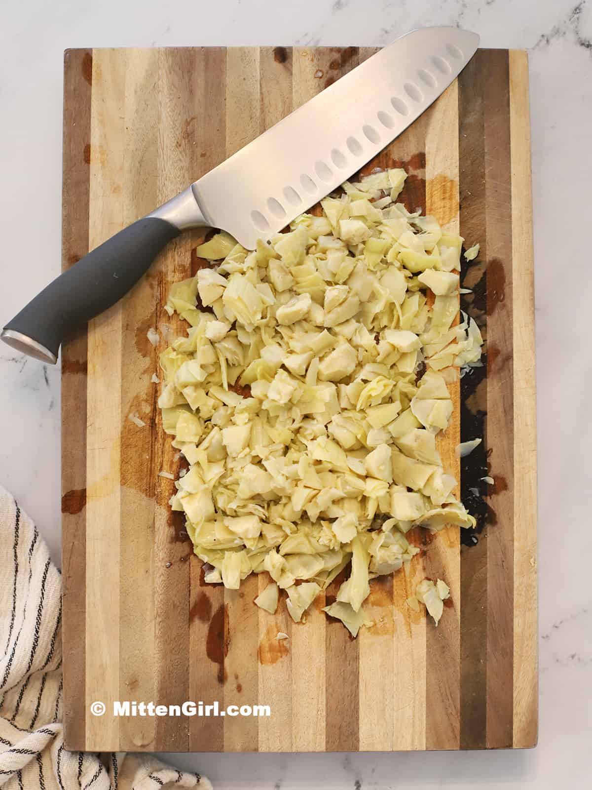 Cutting board full of chopped artichoke hearts. 