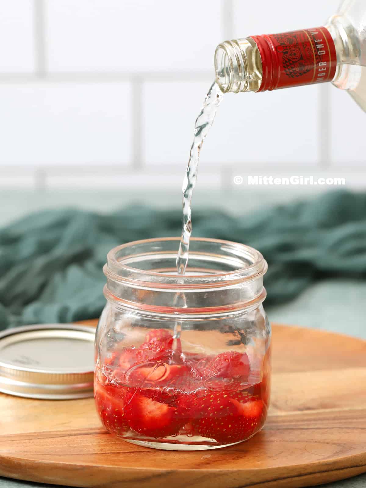 Vodka being poured into a mason jar. 