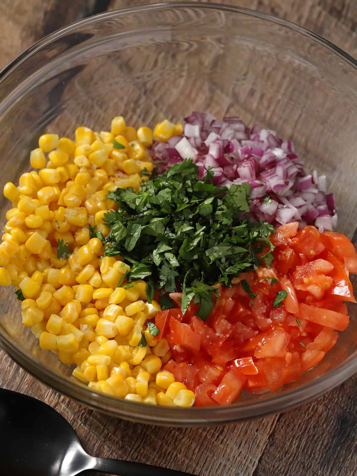 A bowl full of ingredient for corn salsa.