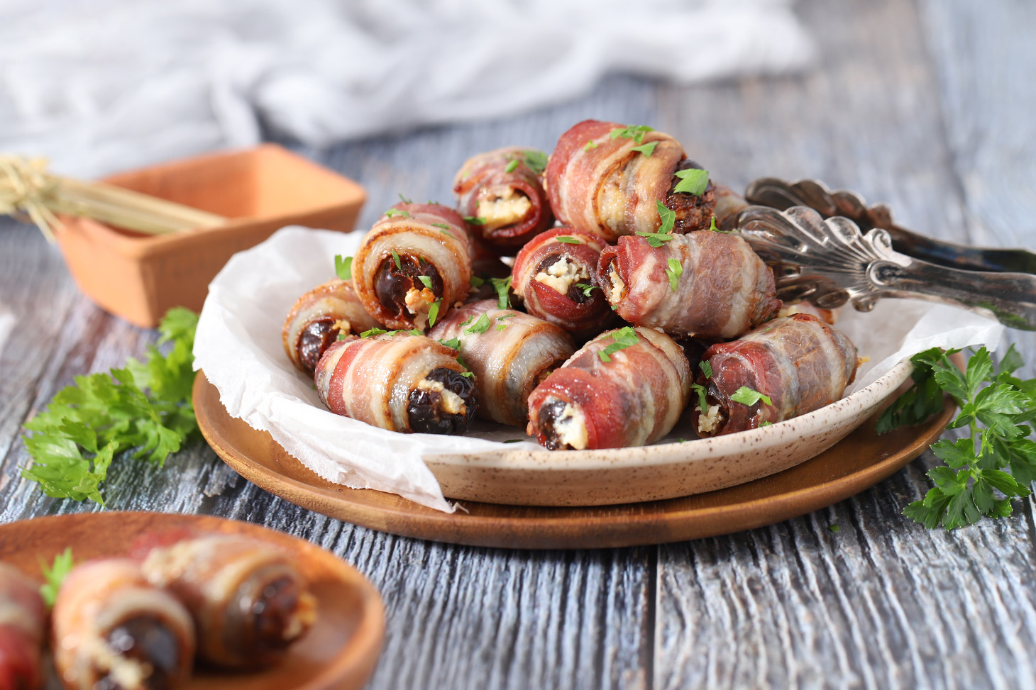 A platter of bacon wrapped dates garnished with parsley.