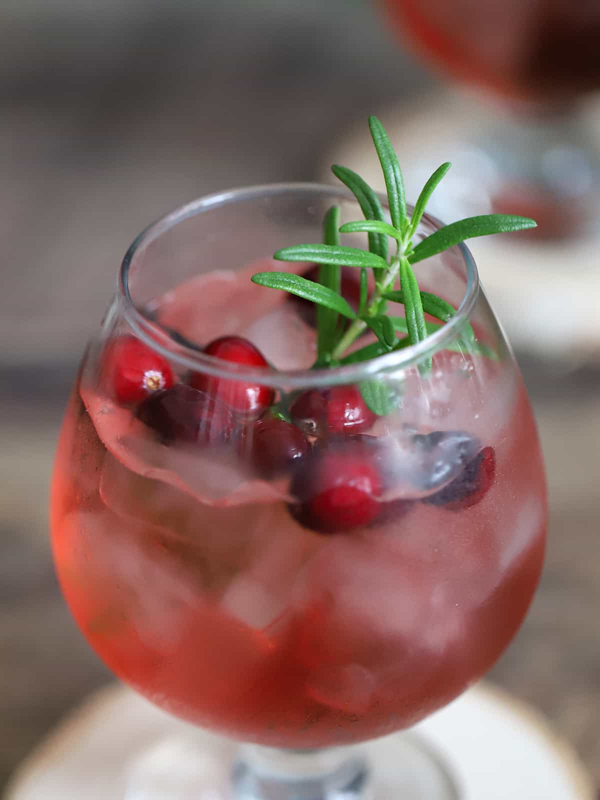 Fresh cranberries and rosemary in a glass of cranberry gin Christmas cocktail. 