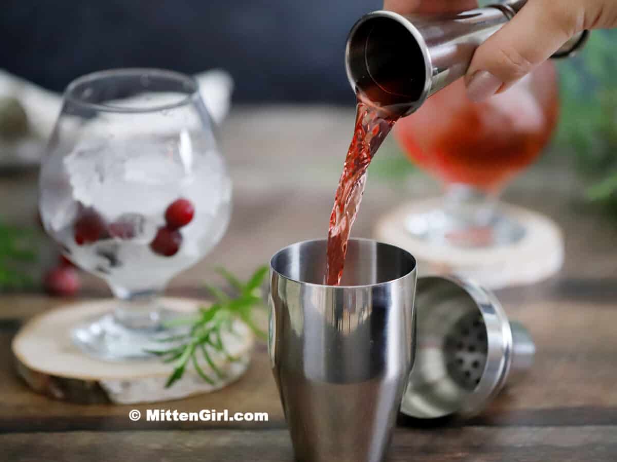 Cranberry juice being poured into a cocktail shaker