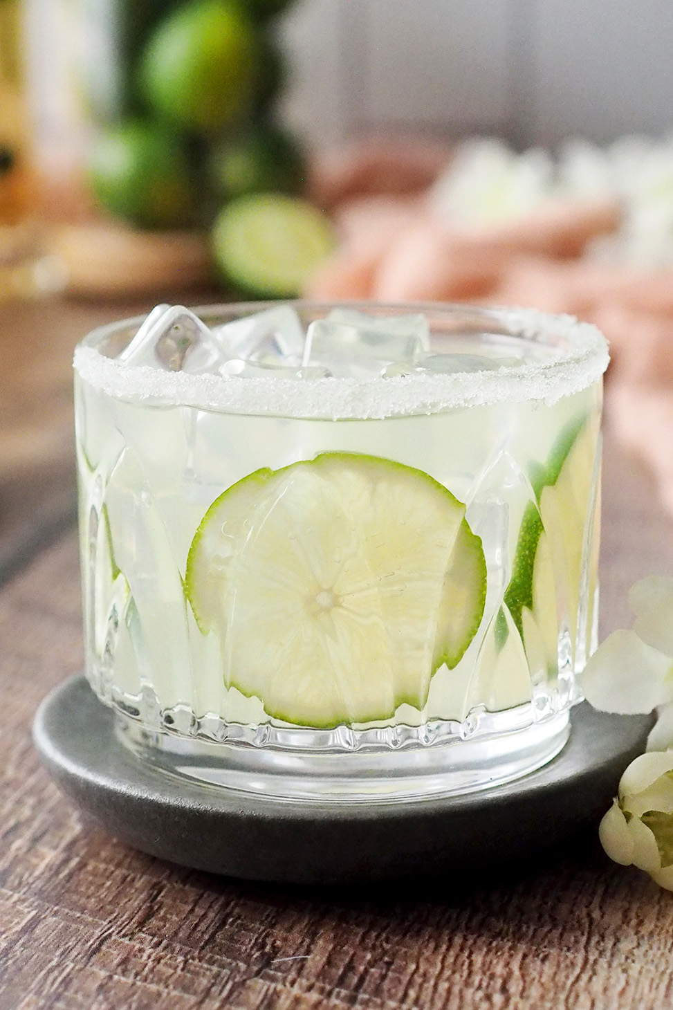 A glass of elderflower margarita garnished with lime slices. 