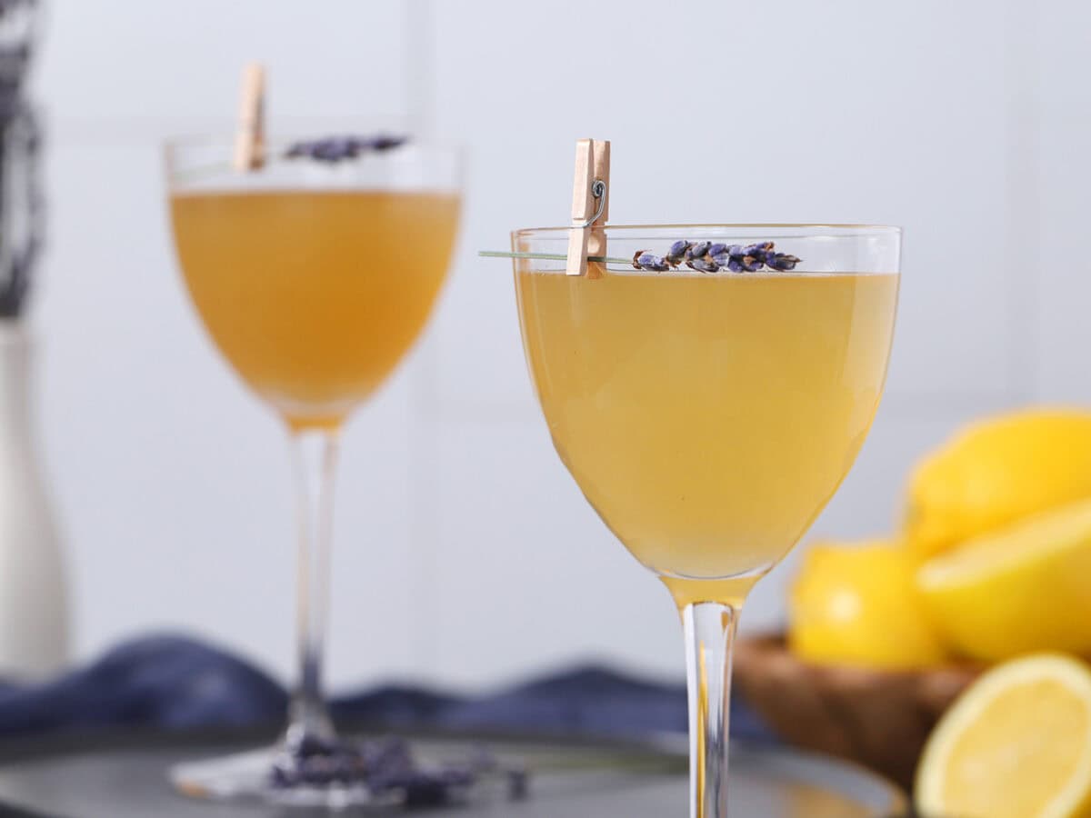 Glasses filled with lavender bee's knees cocktails garnished with sprigs of lavender.