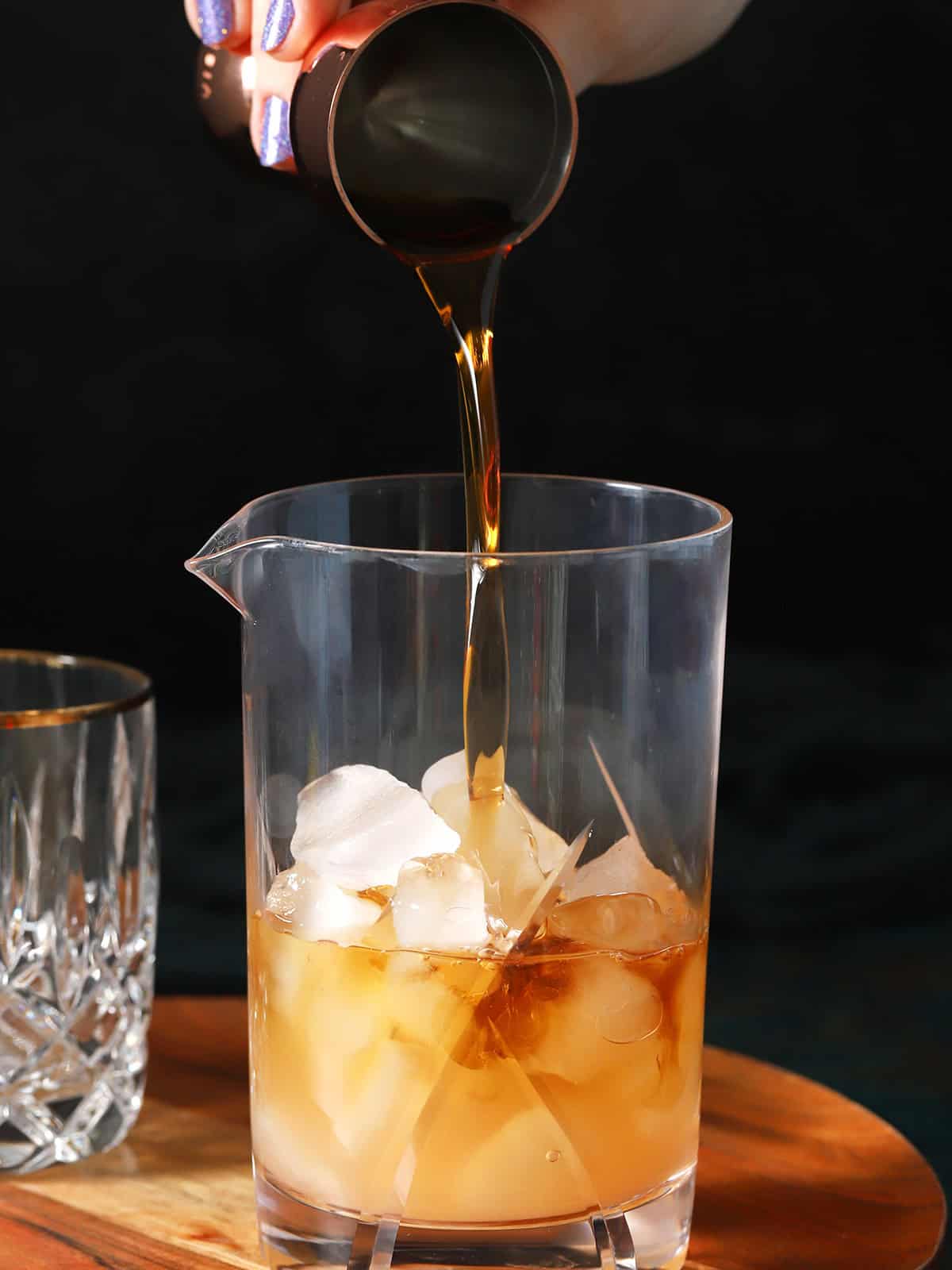 Brown sugar syrup being poured into a mixing glass. 