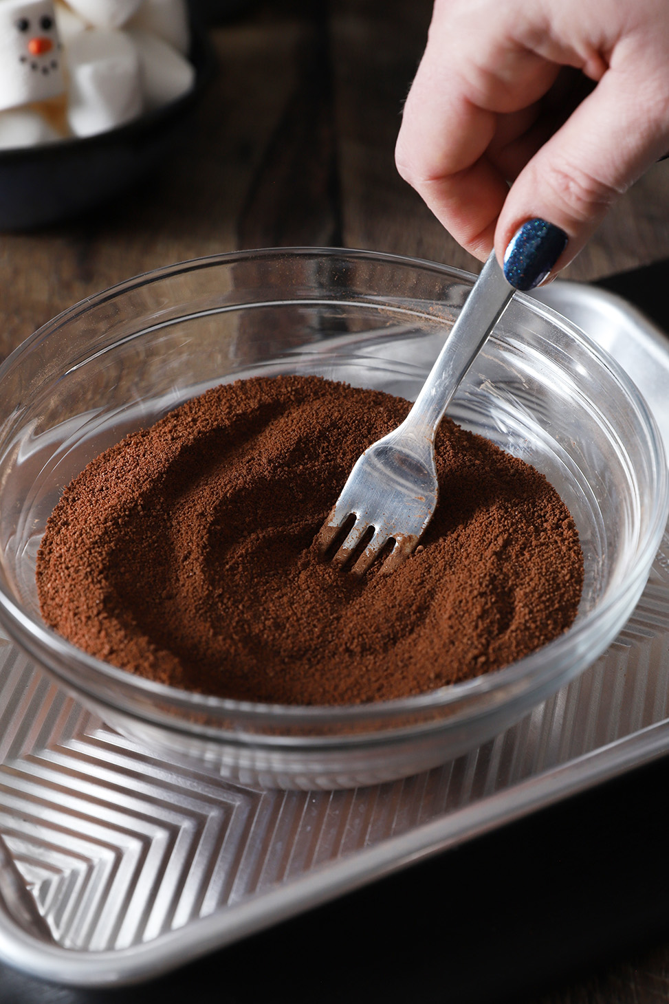 A hand using a fork to mix together all of the hot cocoa ingredients.