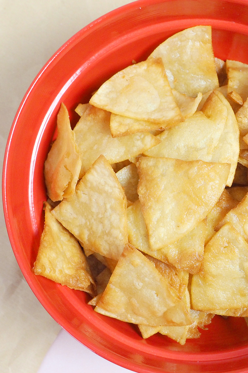 A red bowl filled with homemade tortilla chips.