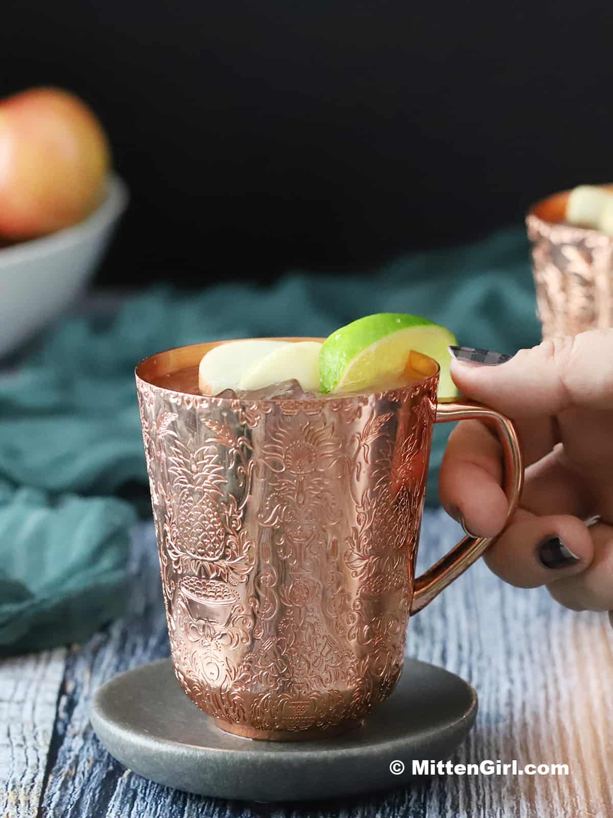A hand reaching out for a copper mug.