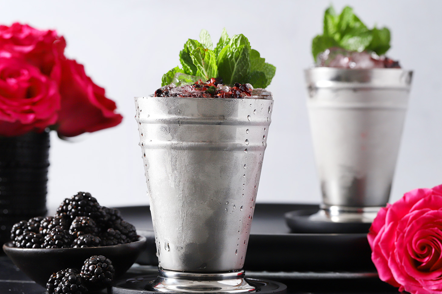 A pair of blackberry mint juleps in silver julep cups with a large bunch of mint for garnish.