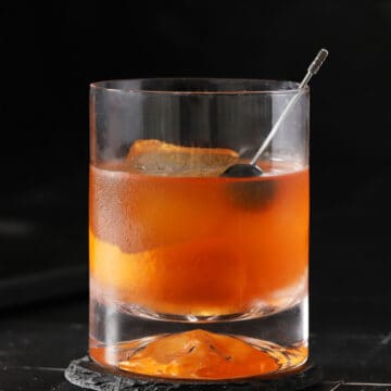 A rocks glass filled with old fashioned cocktail.