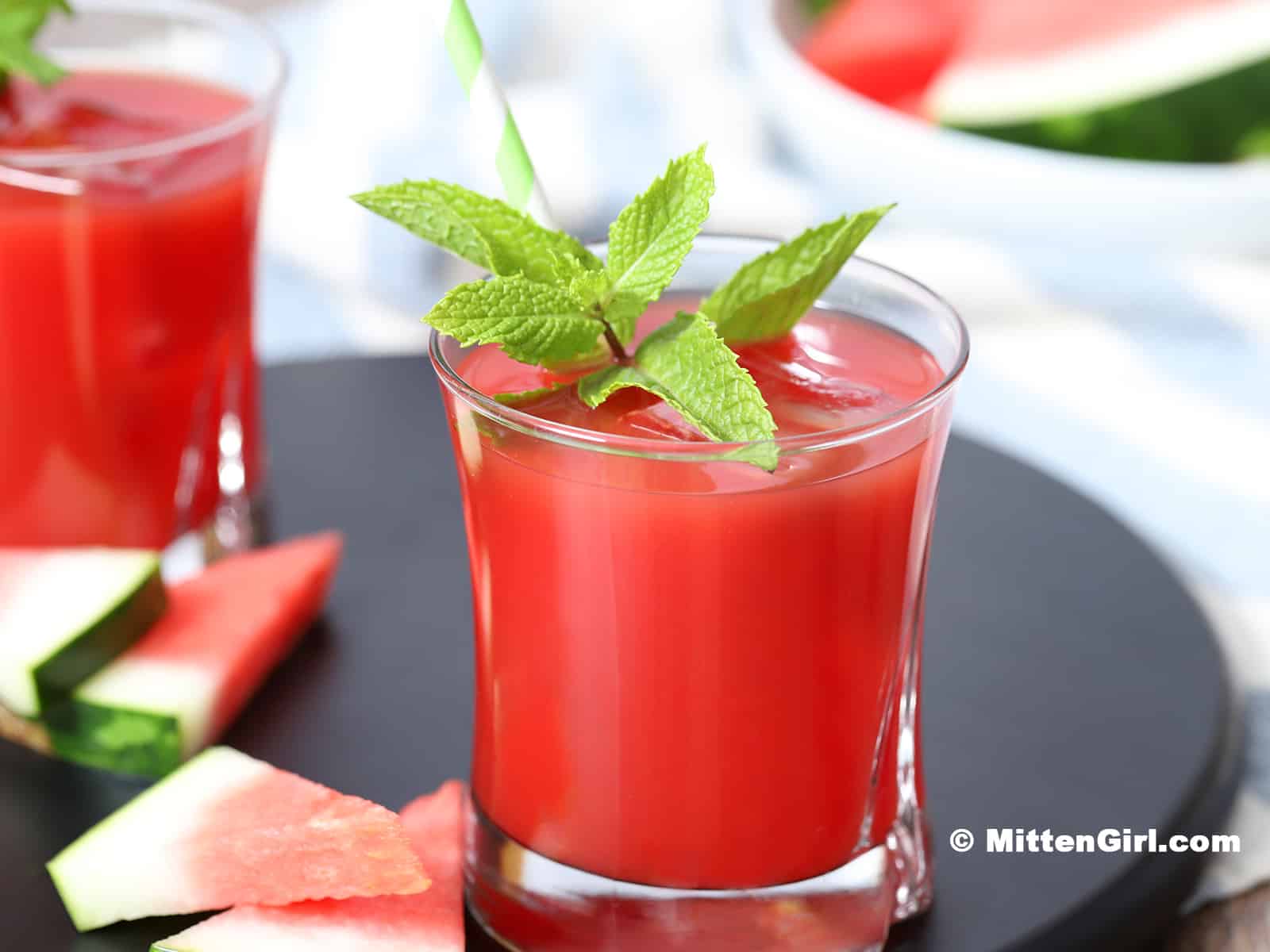 A glass of Watermelon Juice garnished with a sprig of mint.