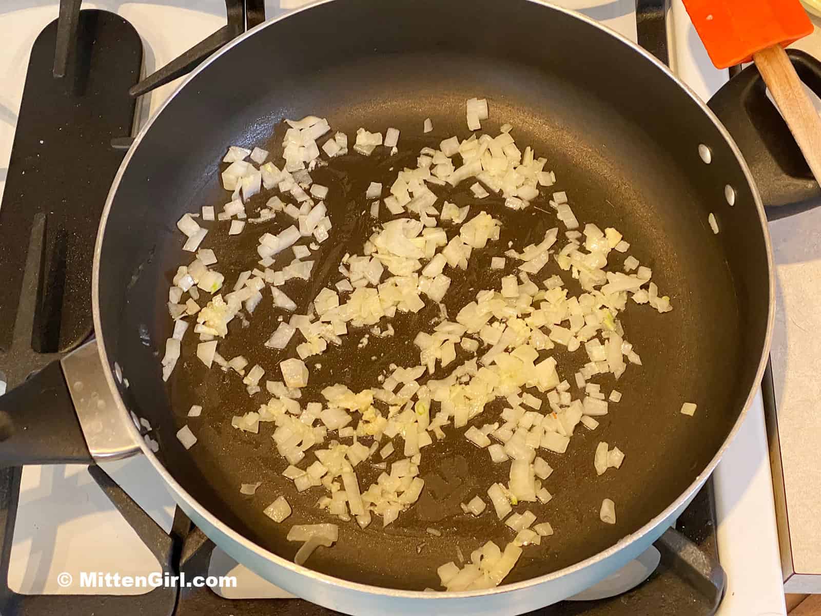 Diced onion cooking in olive oil on the stove.