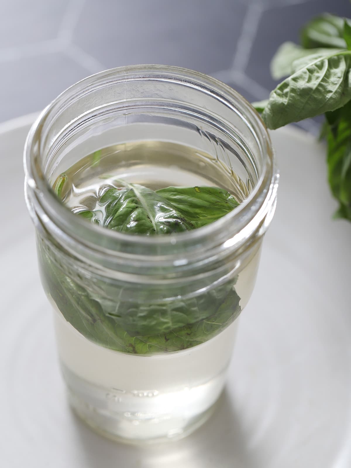 Looking down on an open mason jar of basil syrup. 