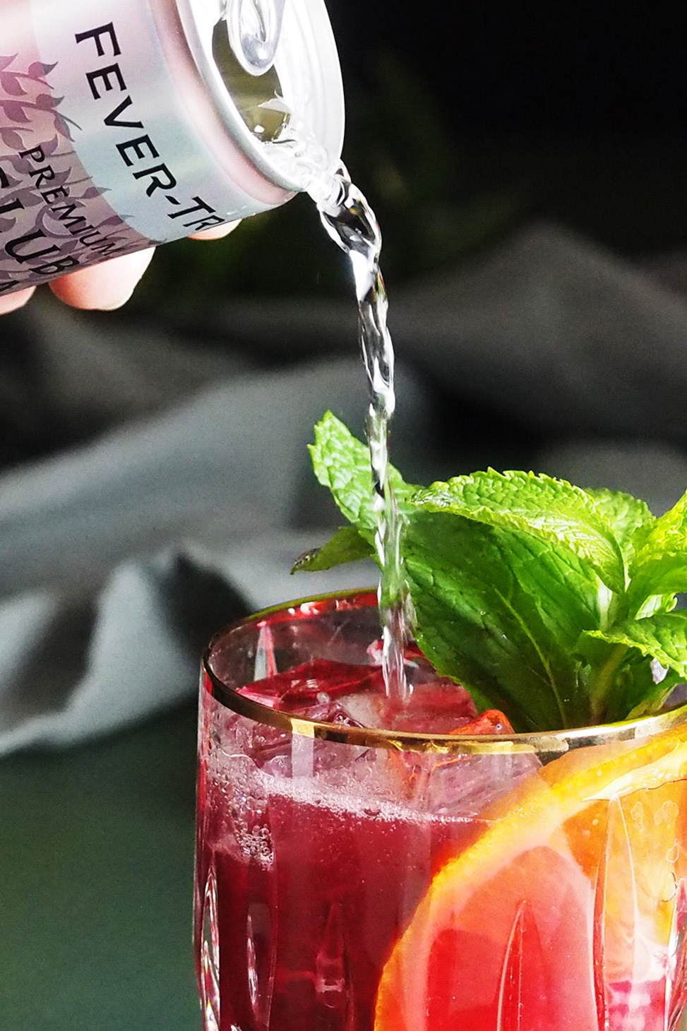Club soda being poured into a glass of blueberry citrus julep.