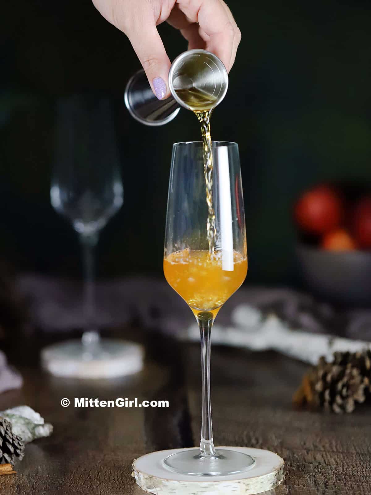 Pouring apple cinnamon infused gin into a champagne flute