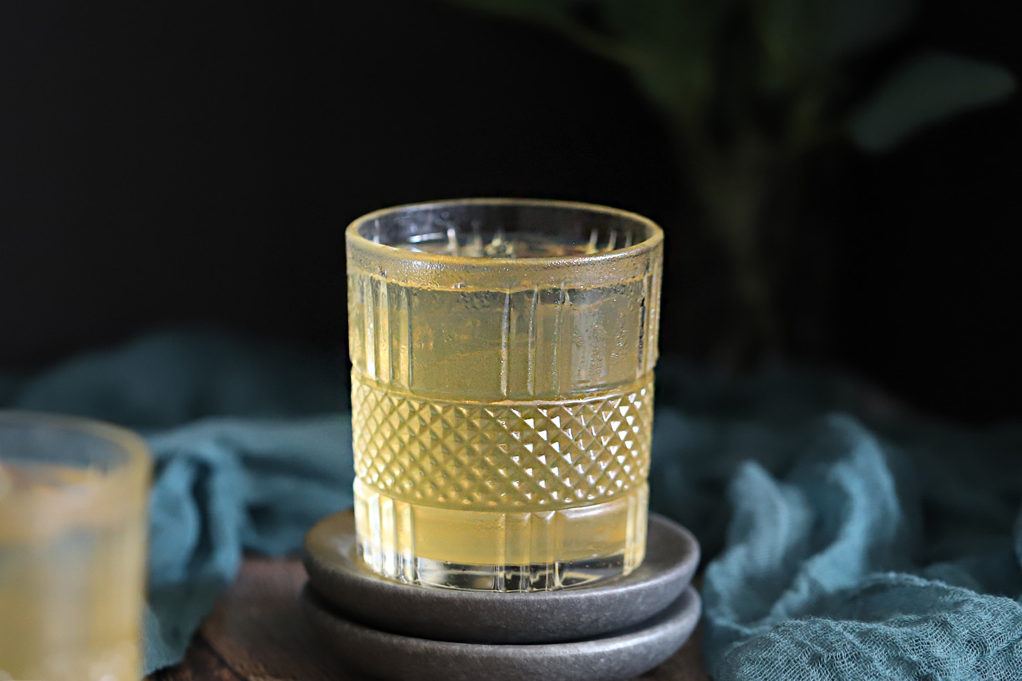 Glasses of bourbon ginger cocktail on grey coasters.