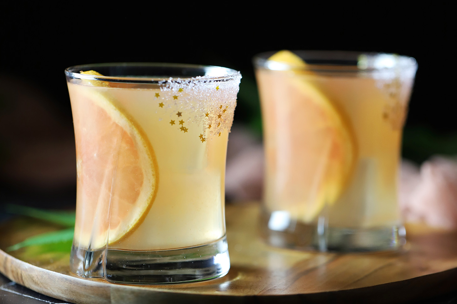 Glasses of grapefruit elderflower gin cocktails garnished with large slices of grapefruit and a sugar rim.