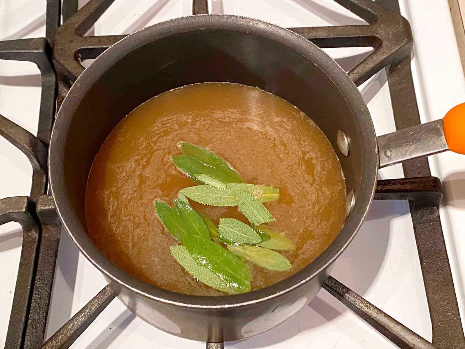 Apple cider, sage, and brown sugar in a pot. 