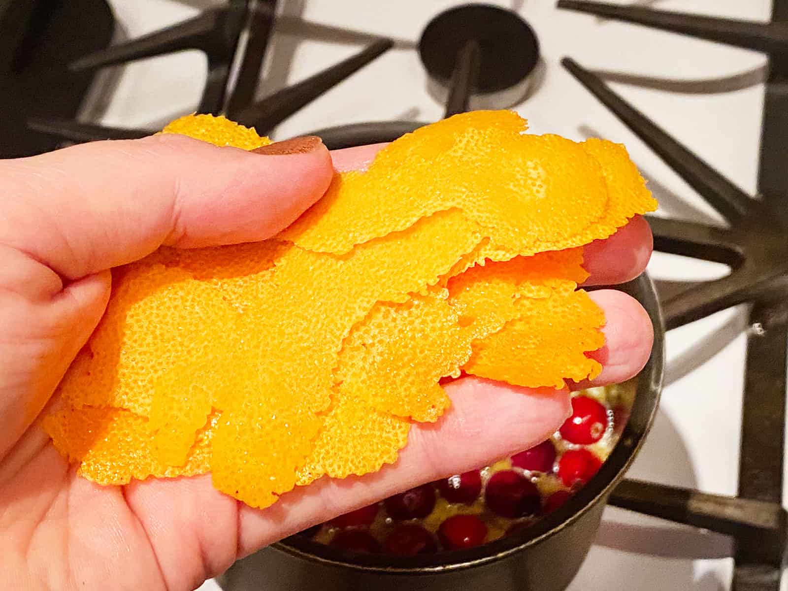 A hand holding some orange peel. 