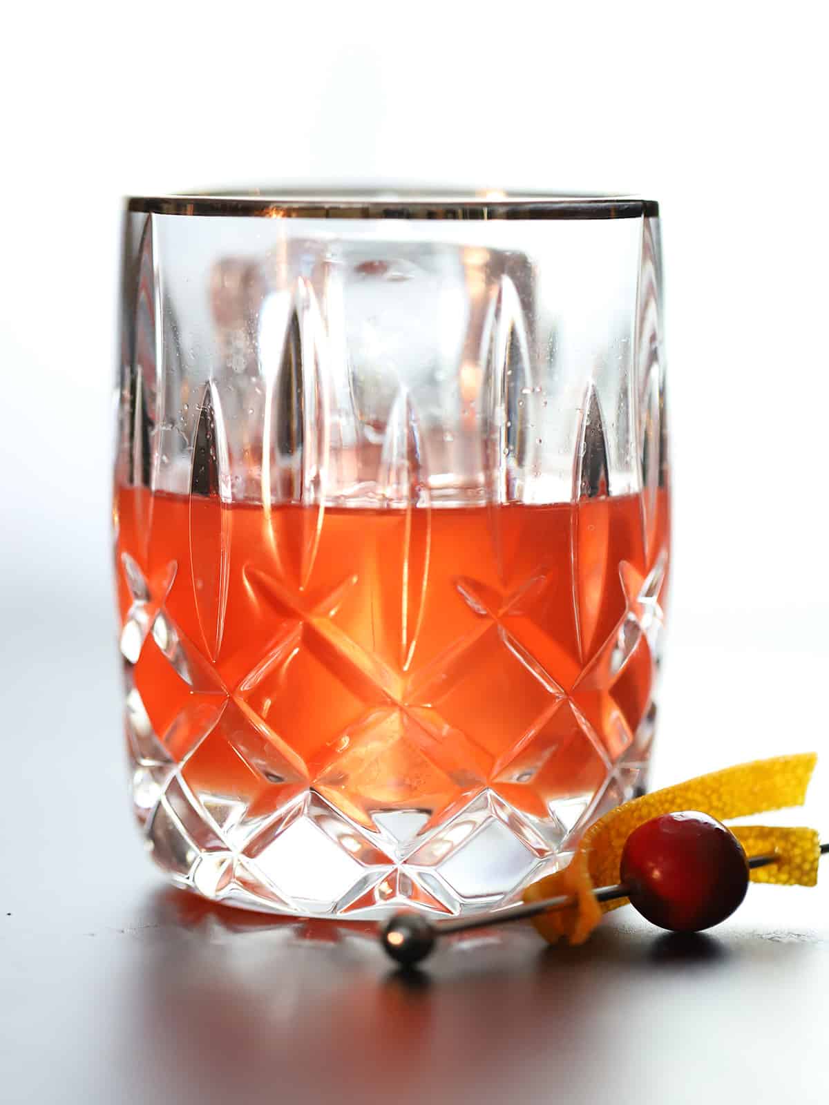 A glass of cranberry old fashioned bourbon cocktail.