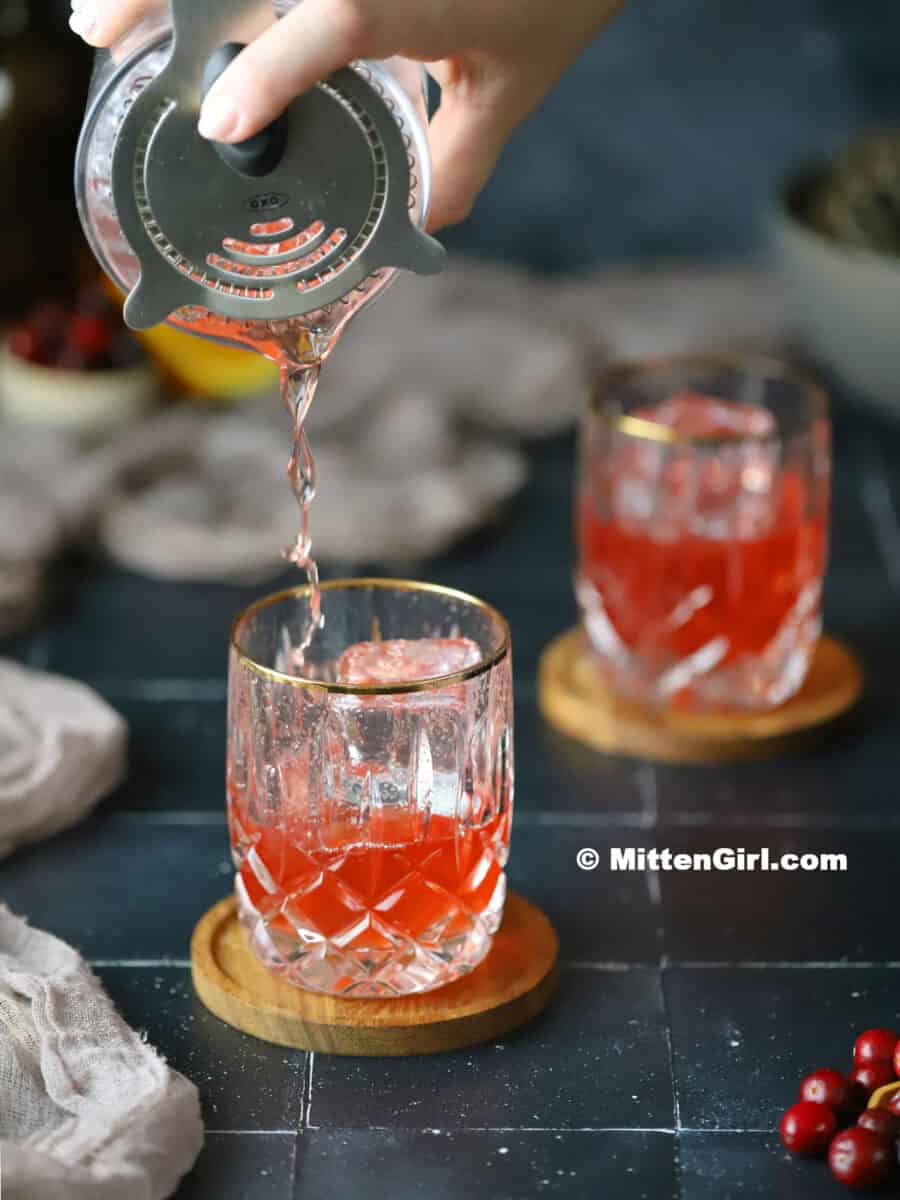 Pouring a Cranberry Old Fashioned into a glass. 