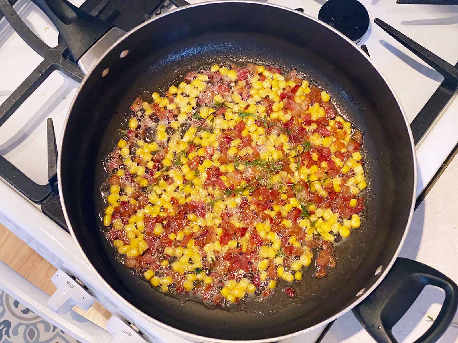 Bacon, corn, and thyme cooking in a pan