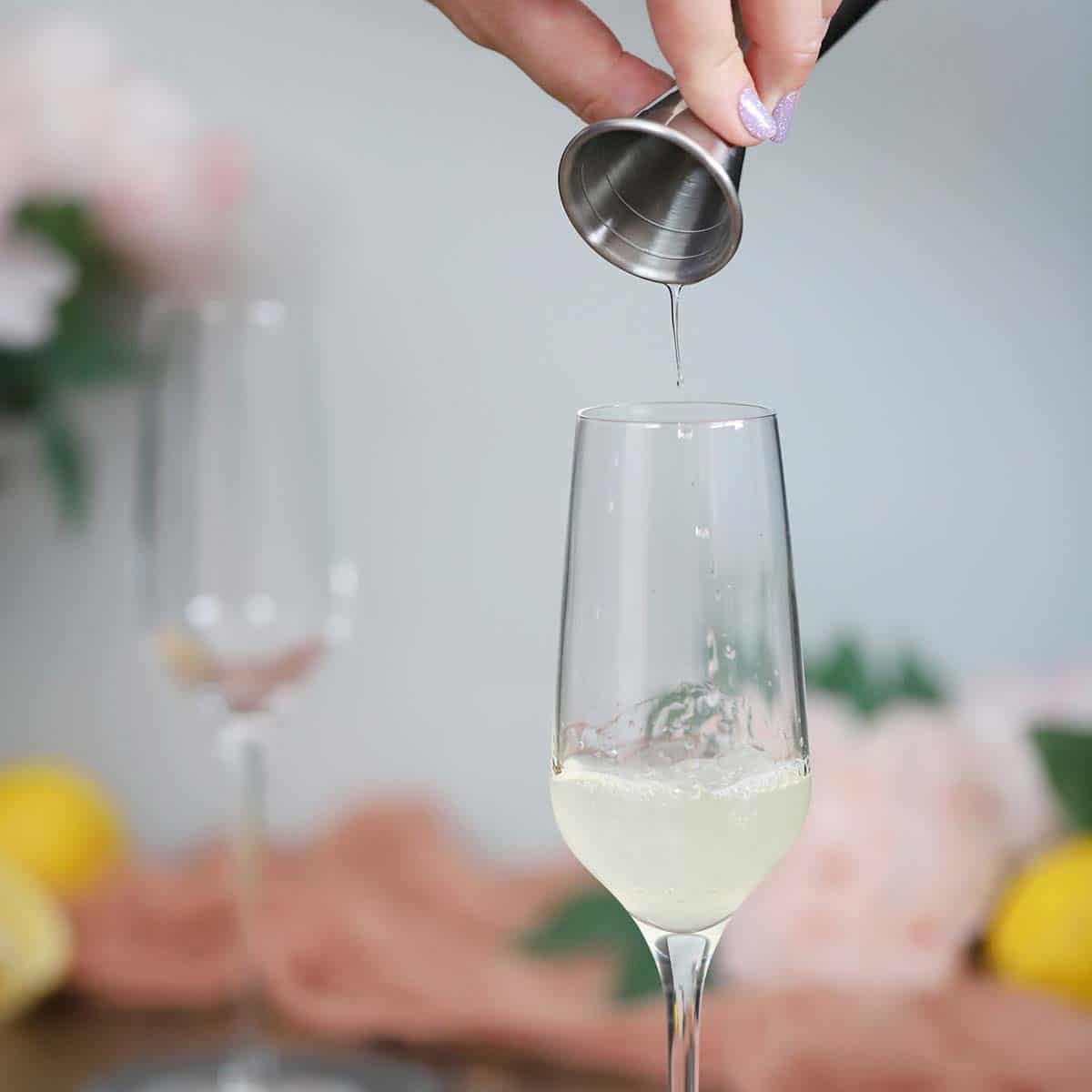 Syrup being poured into a champagne flute. 