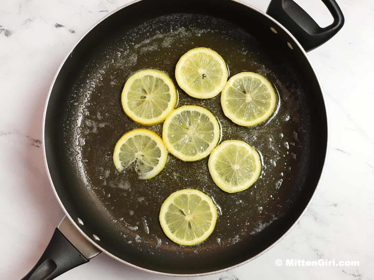 Lemon slices in a skillet with butter and oil.