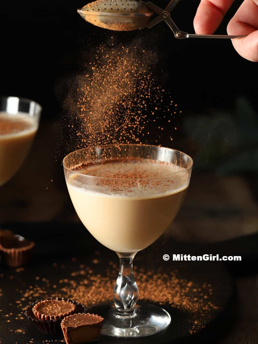 Cocoa powder being sprinkled on top of a cocktail