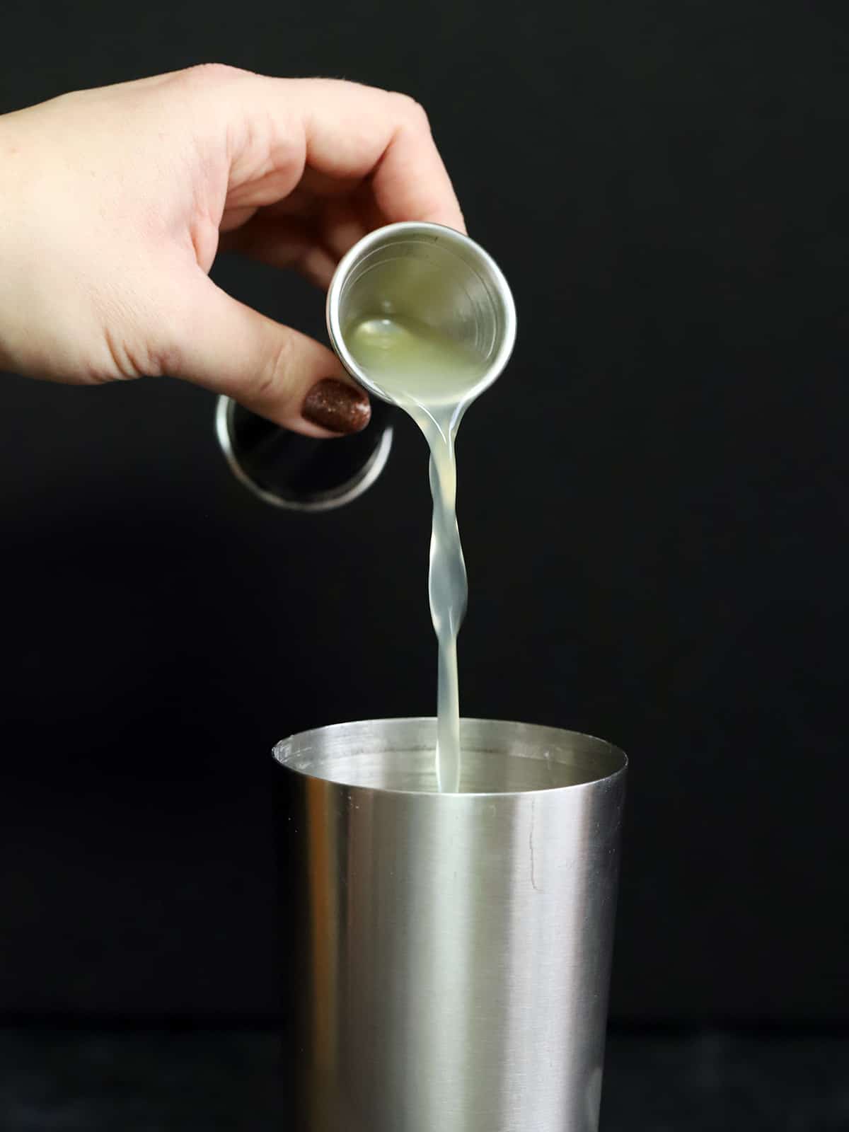 Pouring lemon juice into a cocktail shaker.