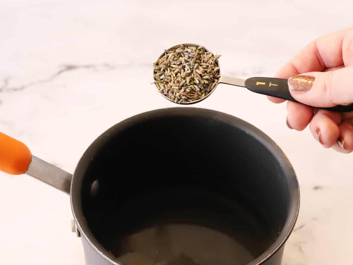 Dried lavender being added to hot simple syrup. 