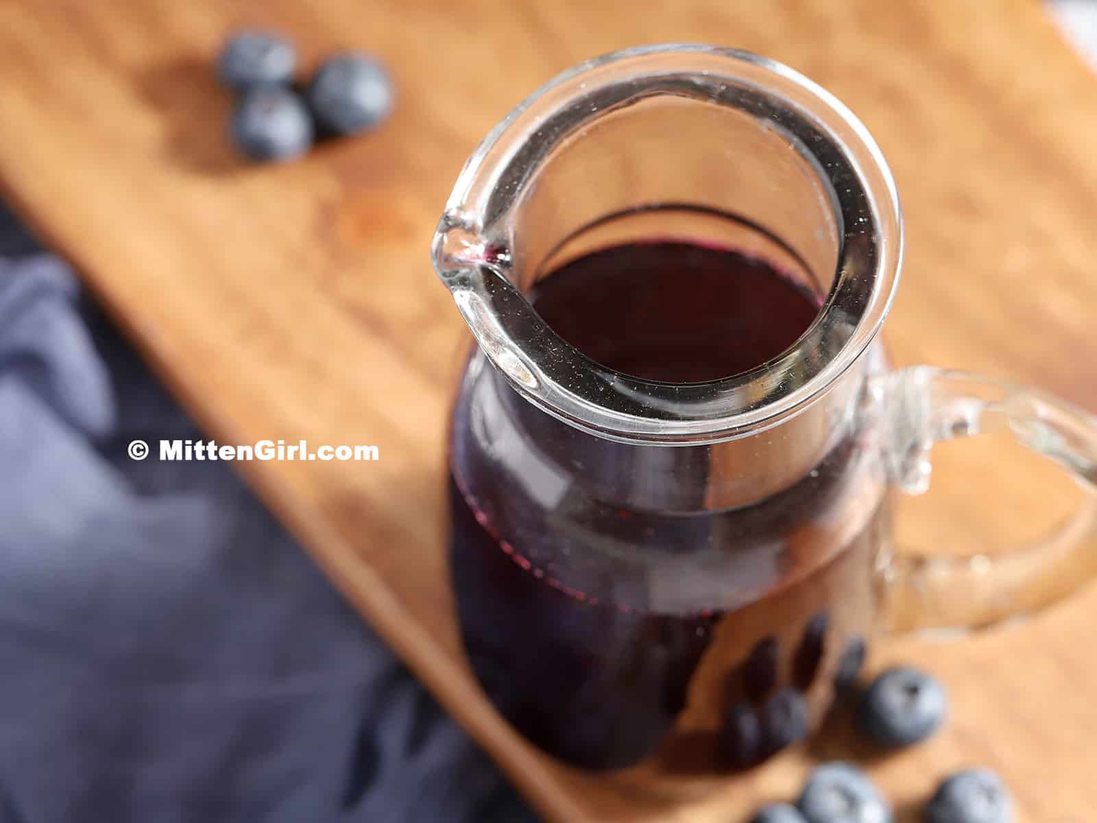 A pitcher of finished blueberry syrup.