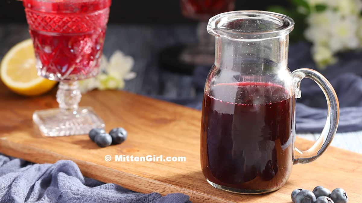 A pitcher of homemade blueberry syrup. 