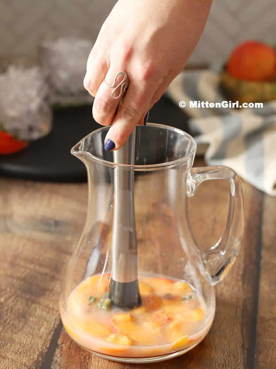 Muddling peaches, thyme and lemon juice in a pitcher. 