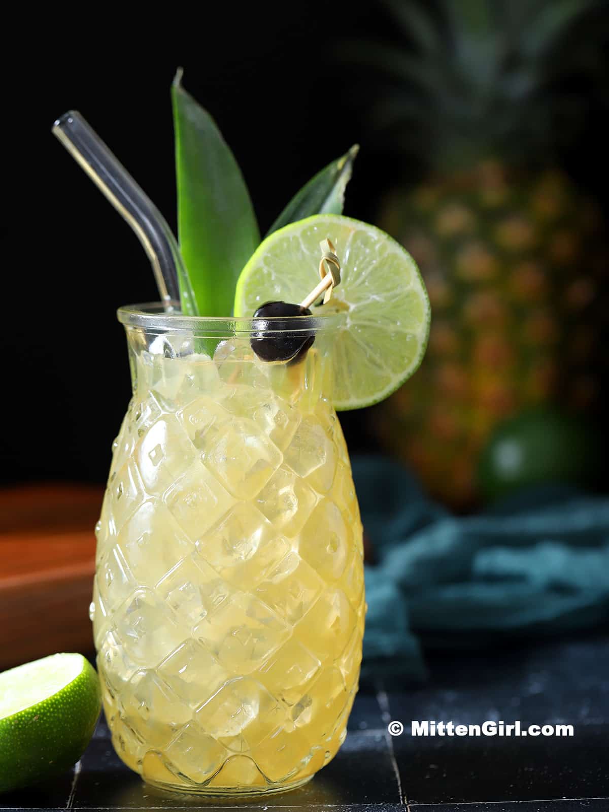 A Mai Tai in a pineapple shaped glass with garnish.