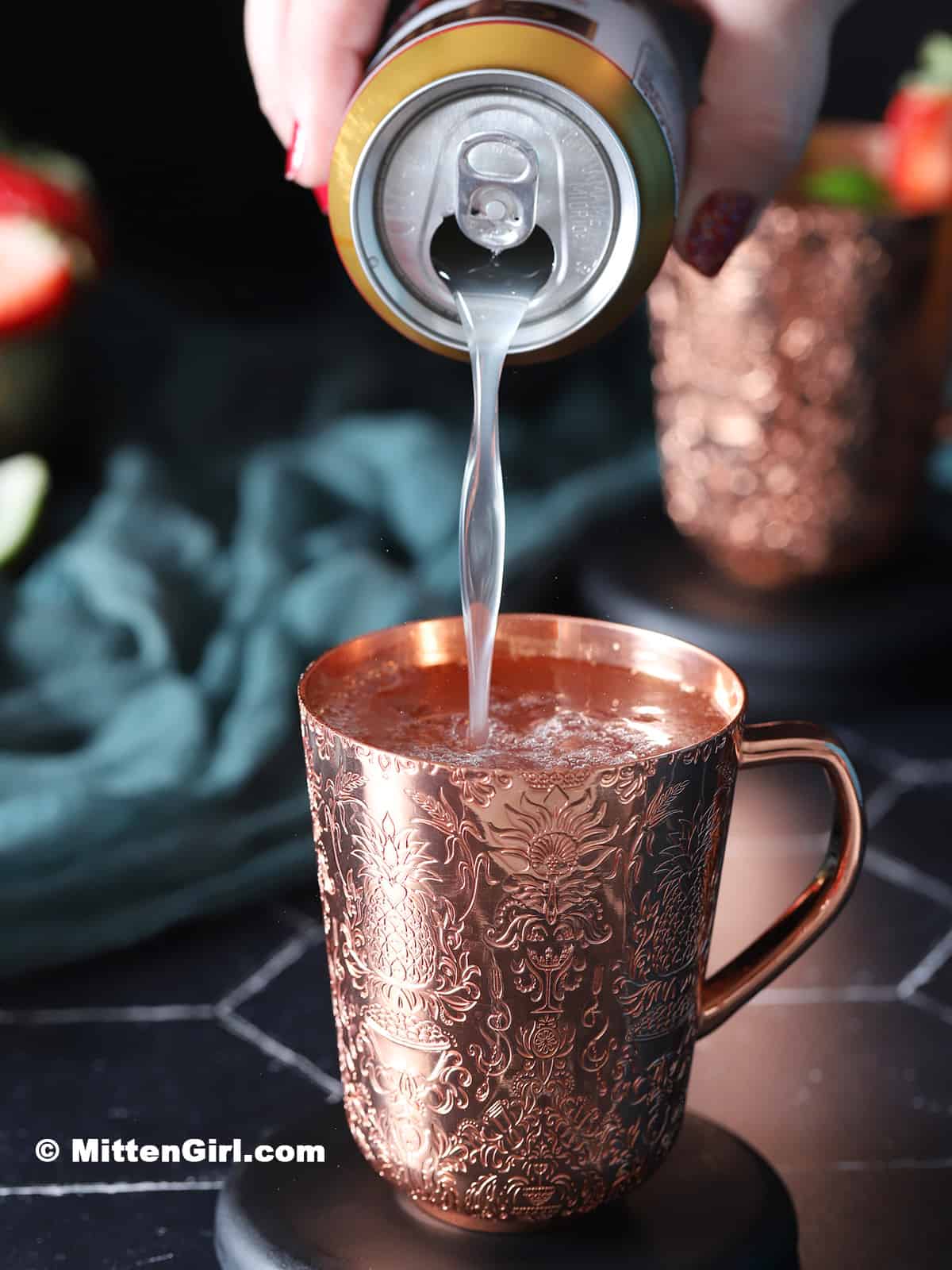 Ginger beer being poured into a copper mug with ice.