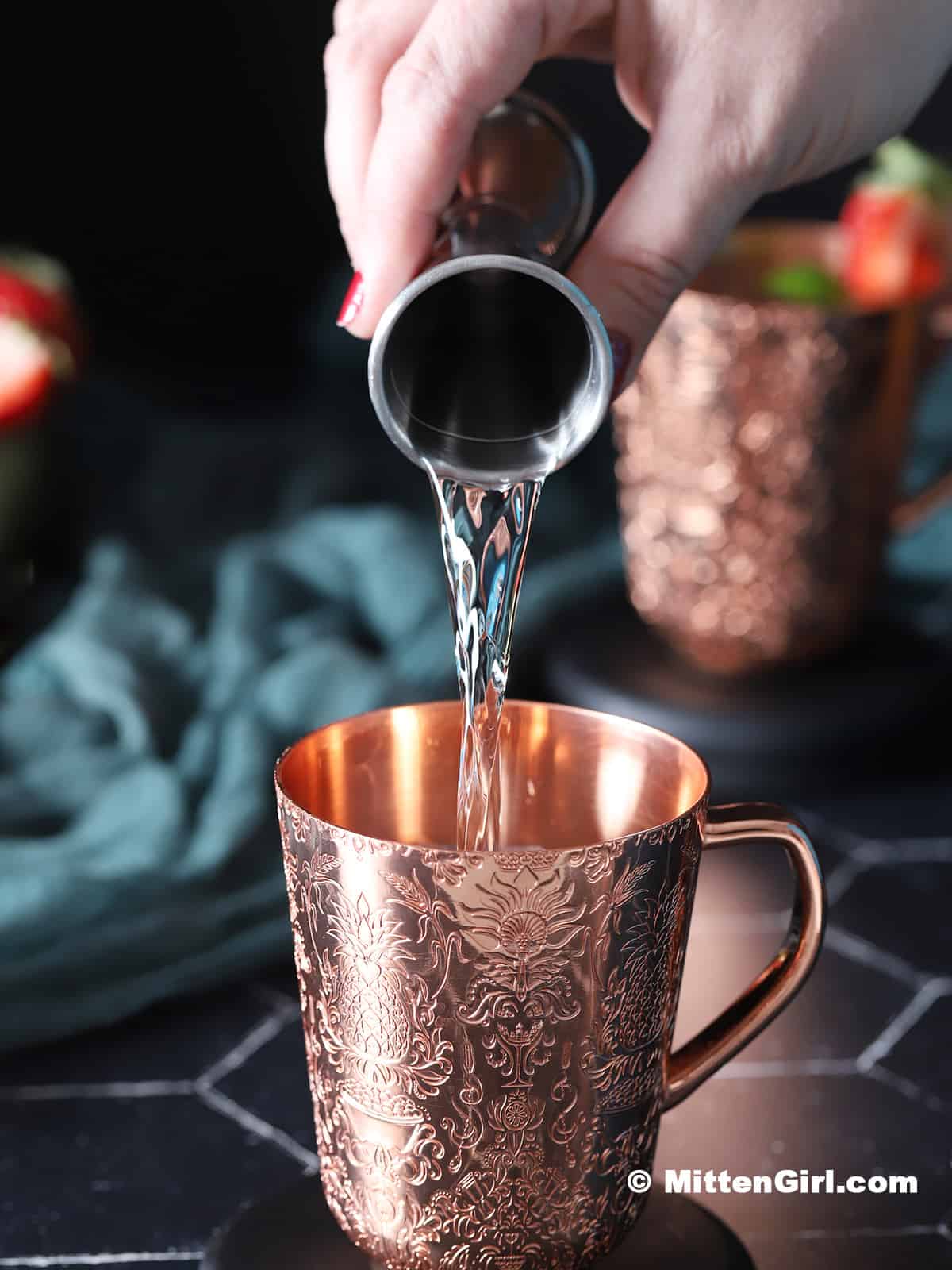 Vodka being poured into a copper mug. 