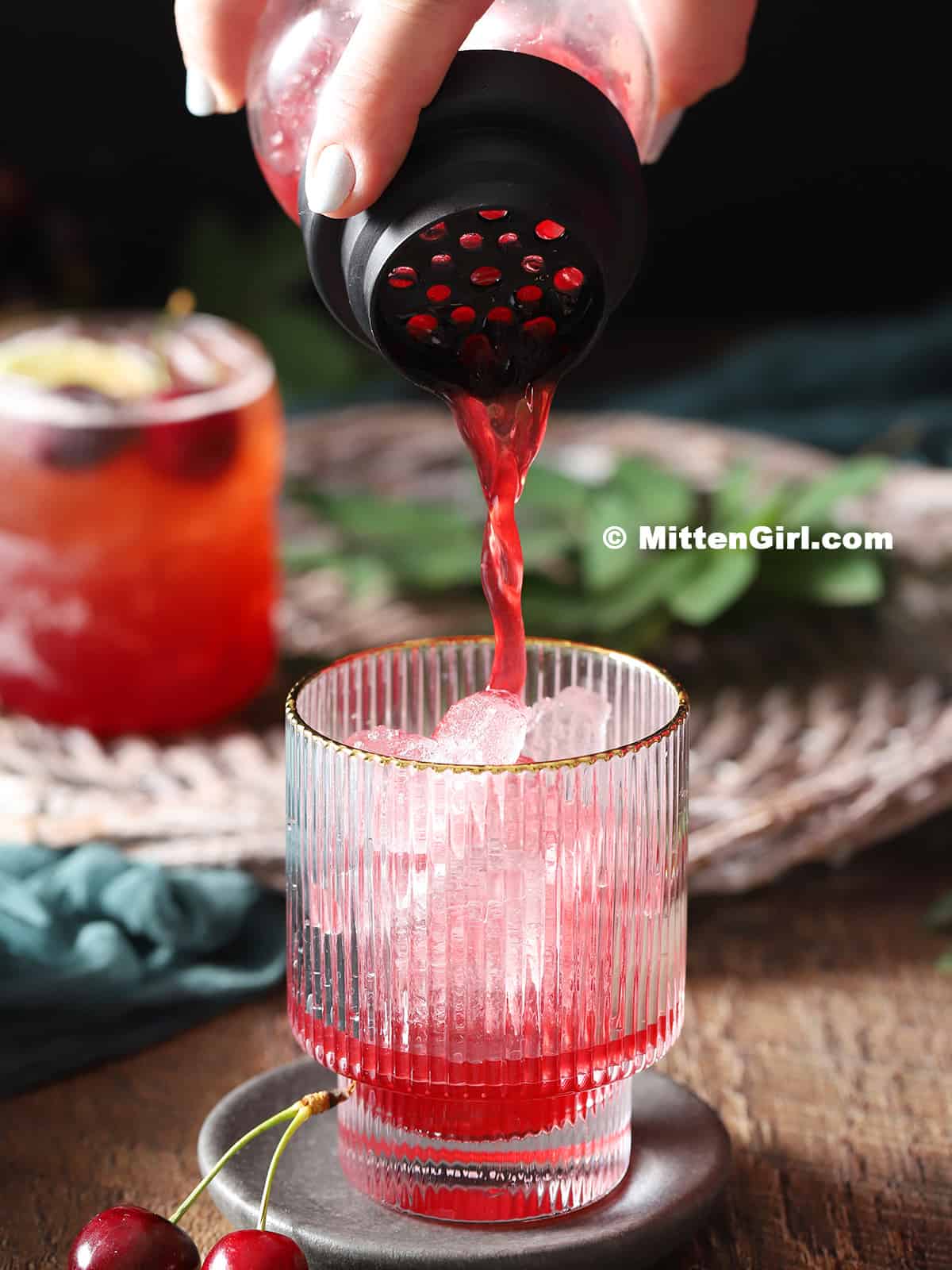 Pouring cherry lime mocktails into a glass of ice. 