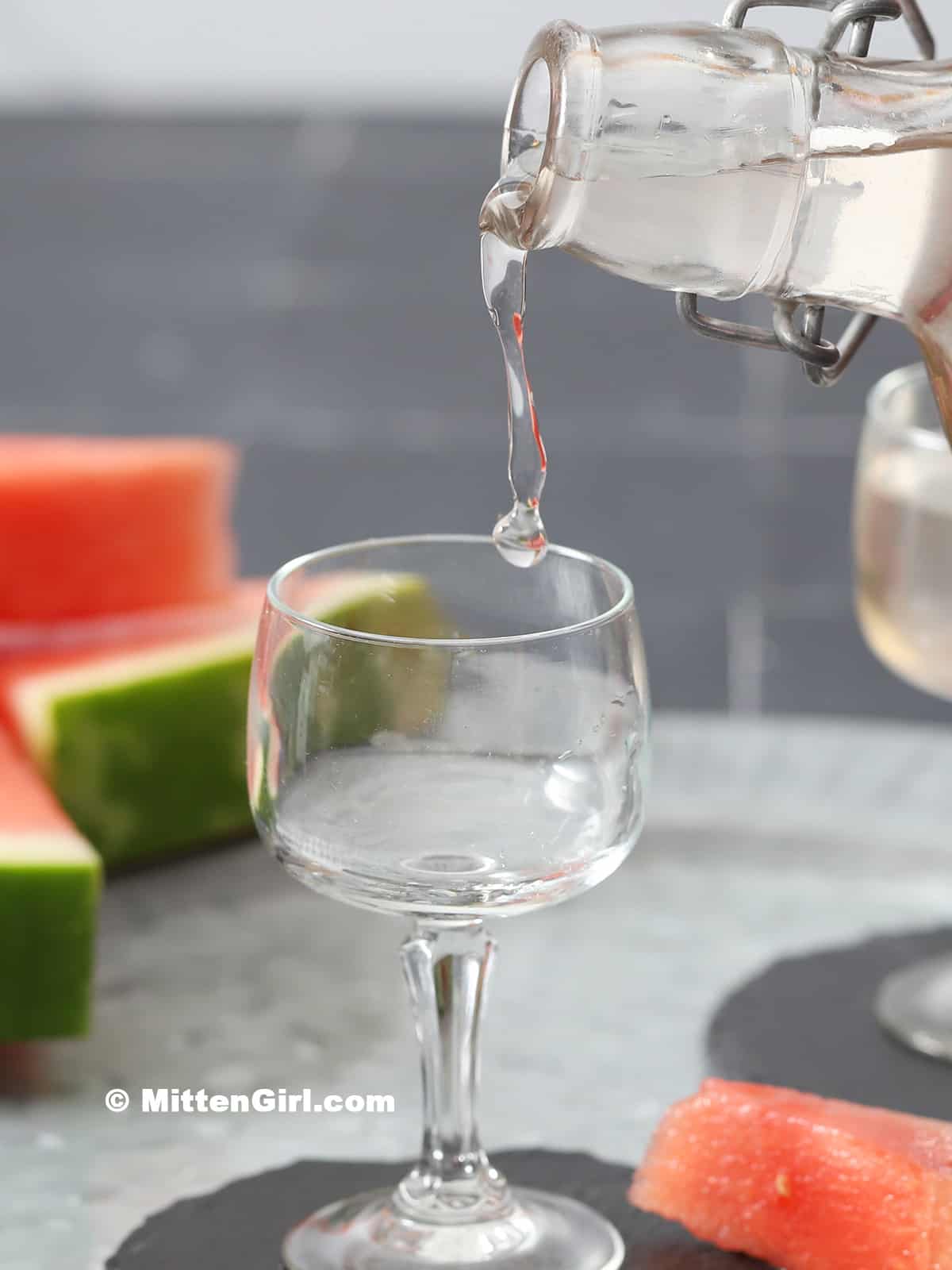 Watermelon vodka being poured into a small glass. 