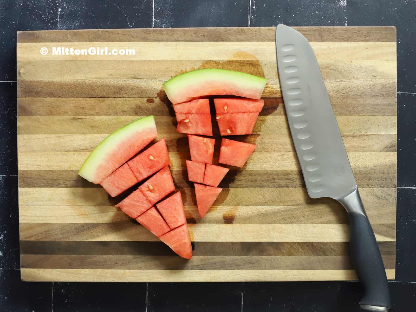 Slices of watermelon and a knife on a cutting board.