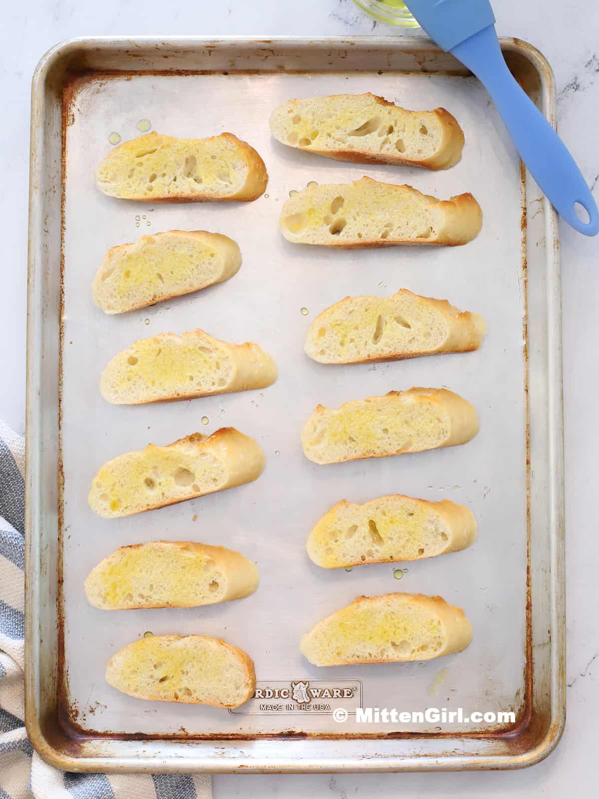 A tray of french bread slices brushed with olive oil. 