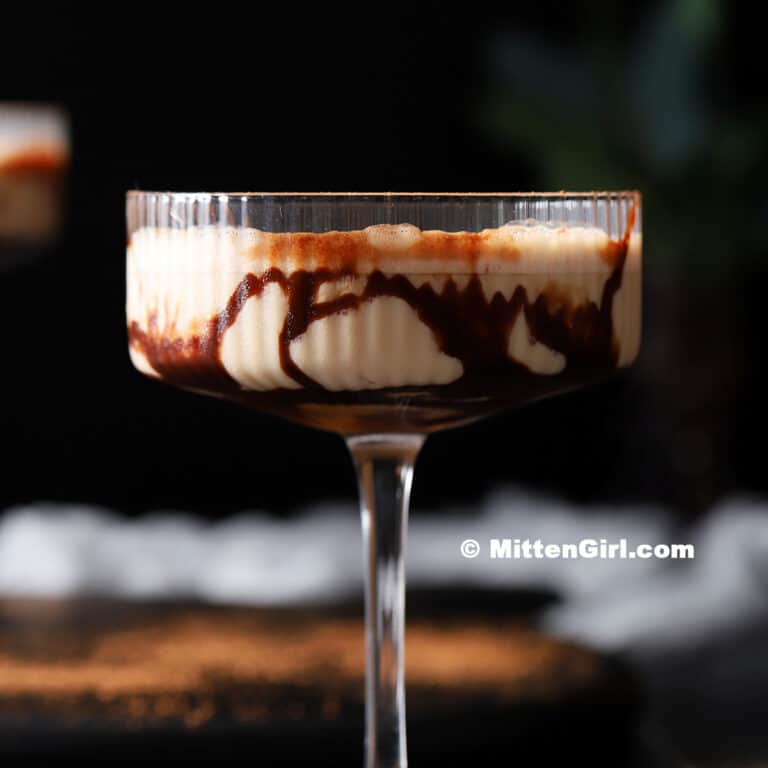 A chocolate-drizzled glass filled with chocolate caramel martini. 